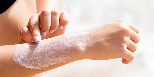 Close up of a person spreading skin care lotion on their right arm